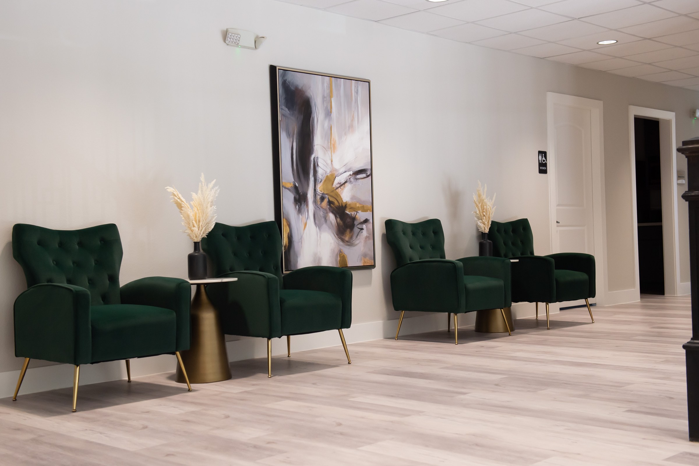 Lobby seating with emerald chairs and abstract art at Bellevana Salon Suites